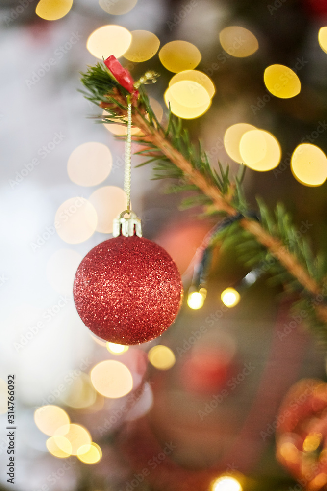 Red ball on a Christmas tree. Christmas glass toy on bokeh background with garlands. Red ball on a Christmas tree. Christmas glass toy on bokeh background with garlands.