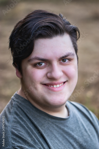 young man in his 20's with dark hair relaxed and happy outdoors in summer