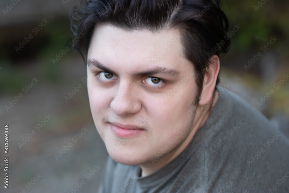 young man in his 20's with dark hair relaxed and happy outdoors in summer young man in his 20's with dark hair relaxed and happy outdoors in summer