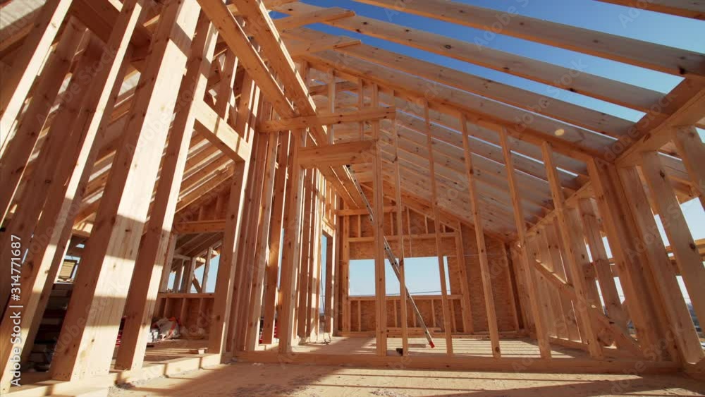 Interior of residential frame house under construction, view of beams and framed walls. Beautiful natural light, sunny day Interior of residential frame house under construction, view of beams and framed walls. Beautiful natural light, sunny day