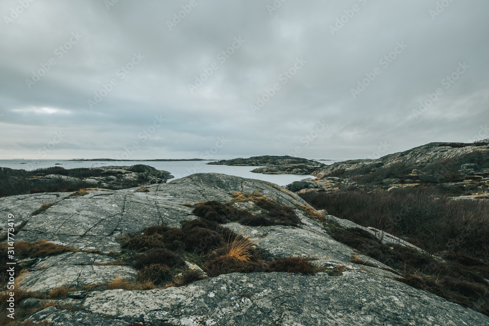 Vrångö, Southern Gothenburg Archipelago / Sweden - A view of sea shore, a rocky landscape of Vrångö island and its scandinavian wooden houses in Sweden during a cloudy day.