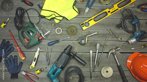 A variety of electro and hand tools and special clothing. Top view. On the table are tools for various types of construction and repair work on wood, metal, concrete, plastic and other materials.