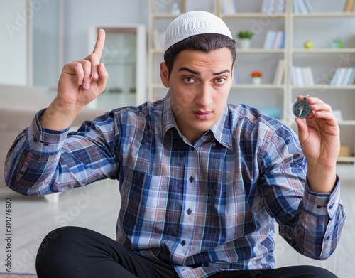 Young muslim man praying at home photo