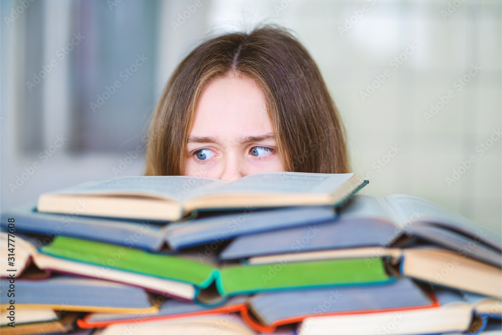Stressed college student tired of hard learning with books in exams tests preparation, overwhelmed high school teen girl exhausted with difficult studies or too much homework, cram concept Stressed college student tired of hard learning with books in exams tests preparation, overwhelmed high school teen girl exhausted with difficult studies or too much homework, cram concept