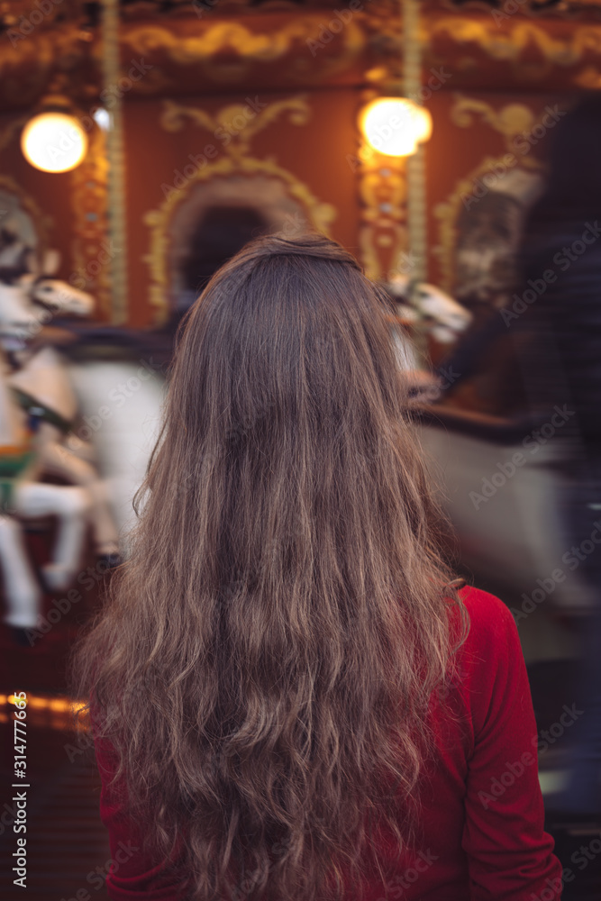 Fototapeta premium Portrait of a beautiful young girl in front of a carousel horse