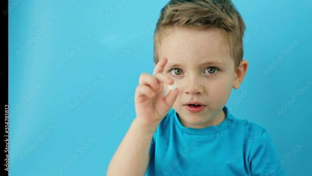 Little child taking pill on blue background. Household danger. Woman health and health care Little child taking pill on blue background. Household danger. Woman health and health care