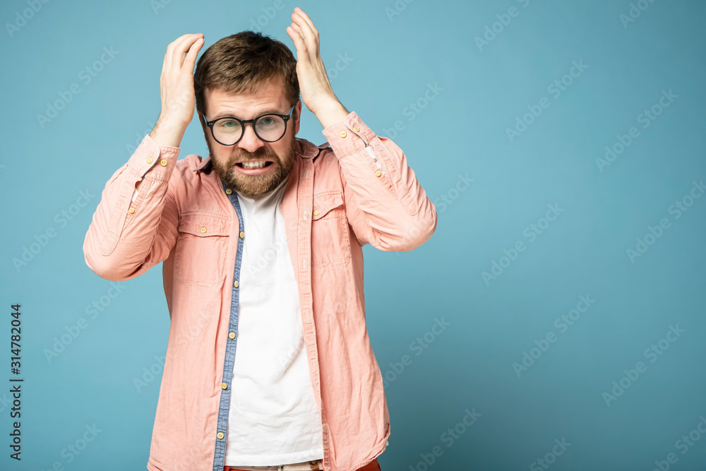 Bearded man in furious. He grin teeth, raised hands to head and looks with hatred at the camera. Copy space. Bearded man in furious. He grin teeth, raised hands to head and looks with hatred at the camera. Copy space.