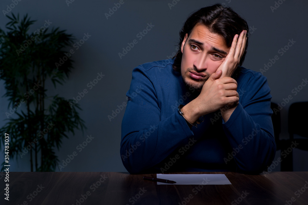 Obraz premium Young convict man sitting in dark room