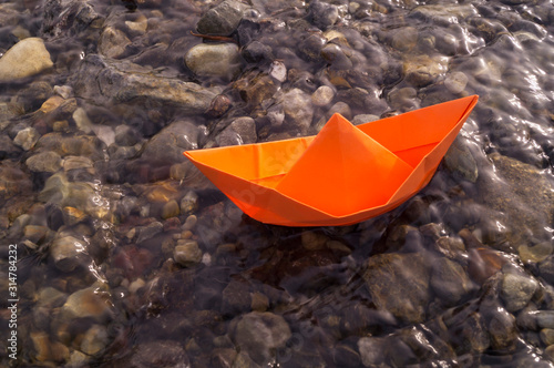 A boat made of colored paper in the snow. Origami handicraft. © Дарья Колпакова