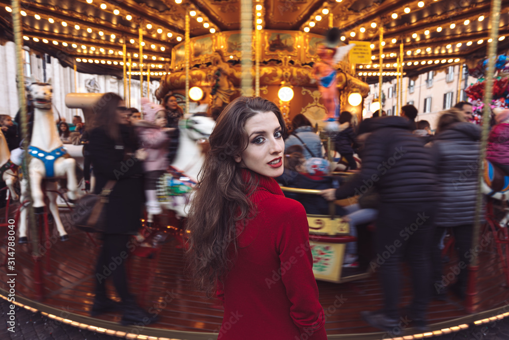 Portrait of a beautiful young girl in front of a carousel horse