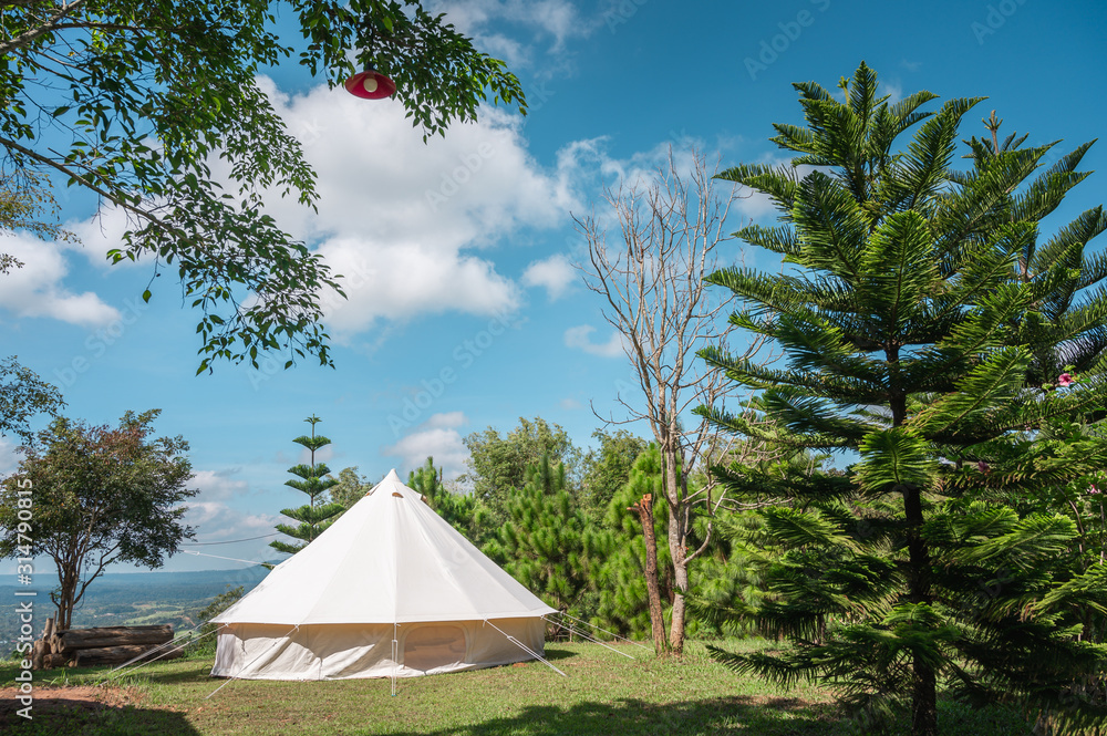 A Vintage white canvas bell shaped camping tent outdoors on the green fields.