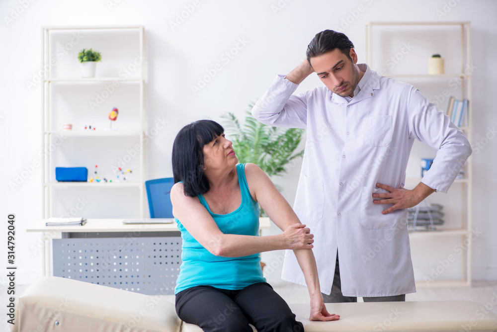 Fototapeta premium Young male doctor examining old female patient