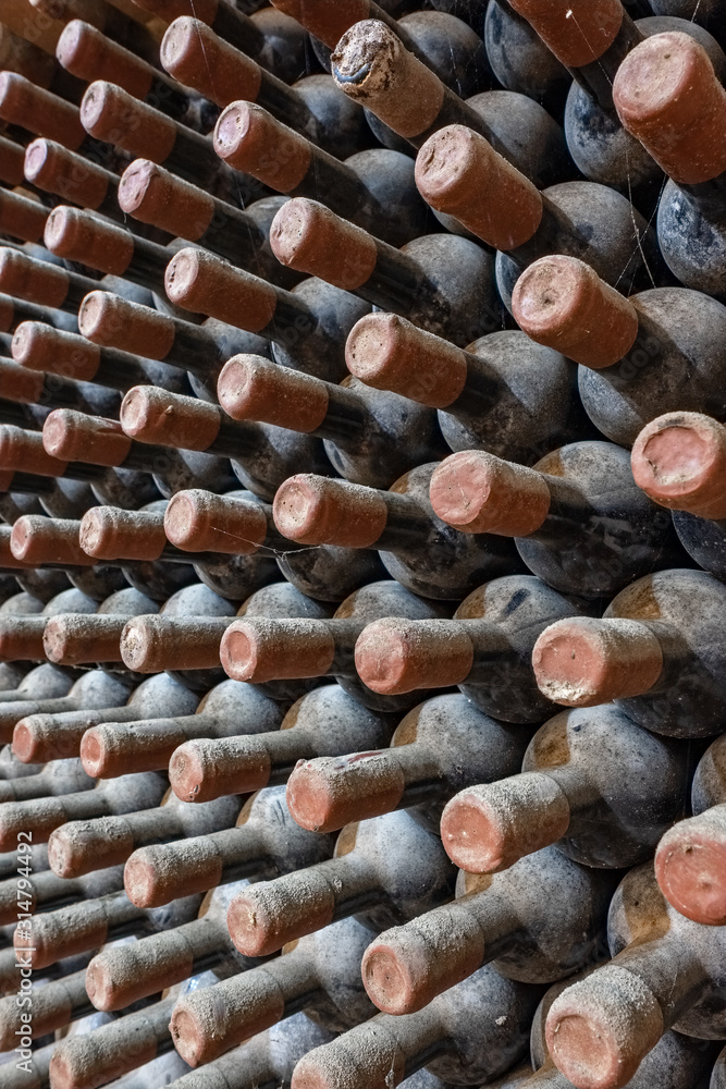 Wine bottles stacked up in old wine cellar close-up background