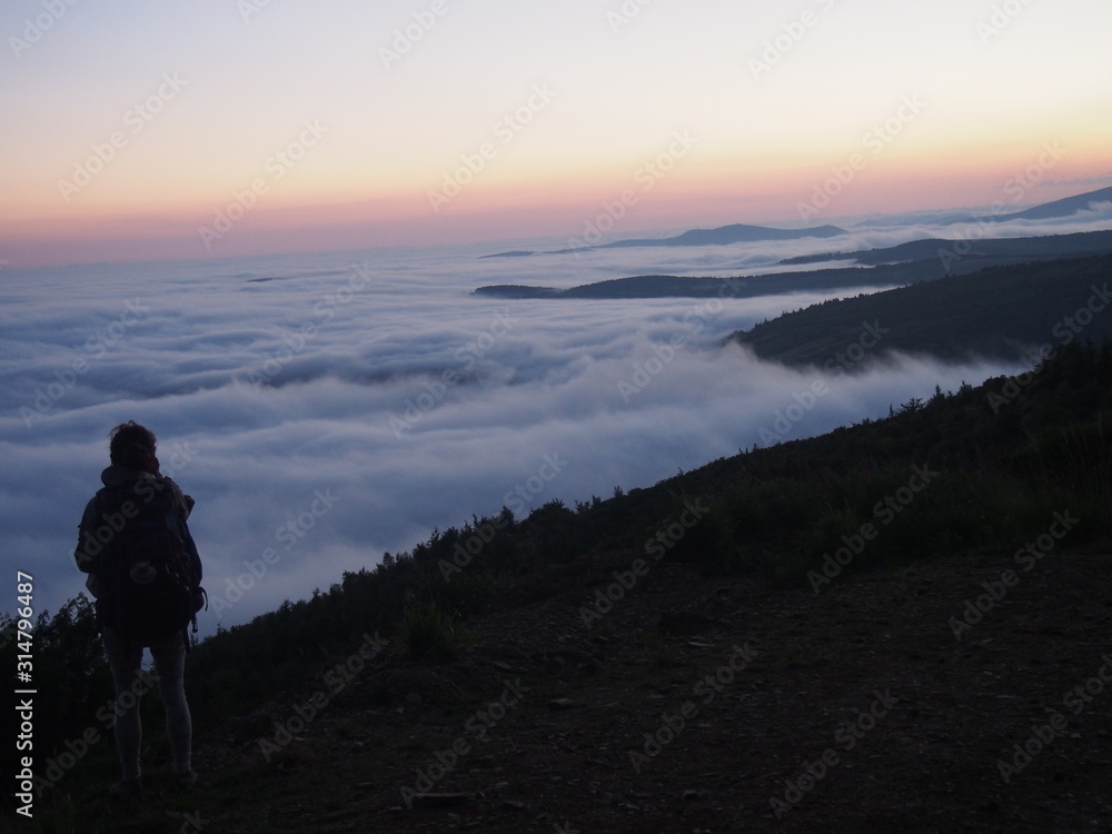 Amazing sea of clouds with sunrise like a rainbow on the road to Santiago de Compostela, Camino de Santiago, Way of St. James, Journey from O Cebreiro to Calbor, French way, Spain