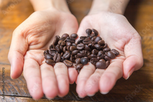 Coffee beans on a woman's hand in a coffee shop.