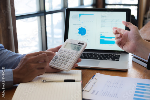 Sitting and working, consulting and suggesting work, checking work reports with a calculator in a business office.