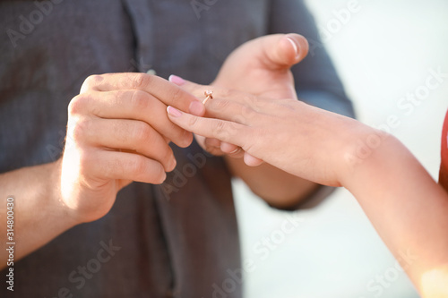 Young man putting ring on finger of his fiancee after marriage proposal  closeup