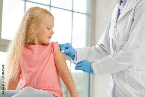Doctor vaccinating little g...