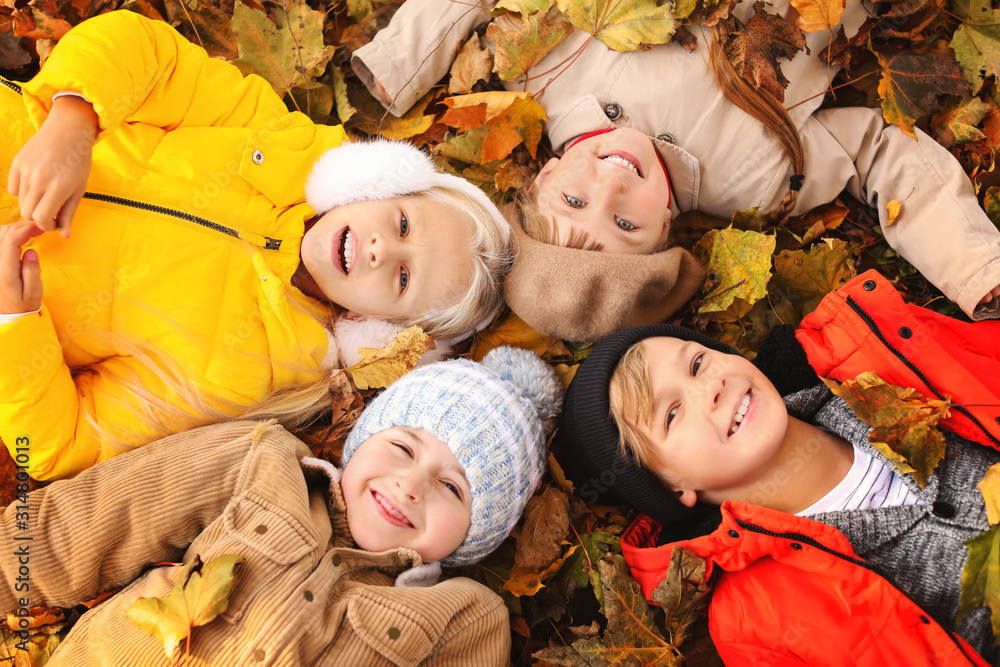 Cute little children lying on leaves in autumn park Cute little children lying on leaves in autumn park