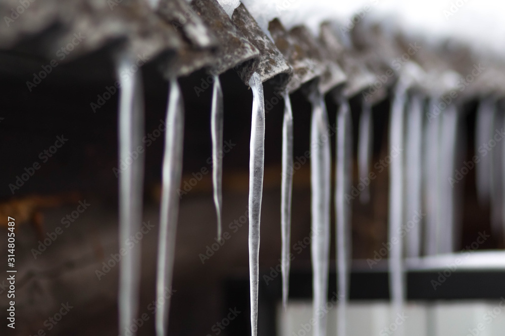 Icicles hang on the old roof. Close up Icicles hang on the old roof. Close up