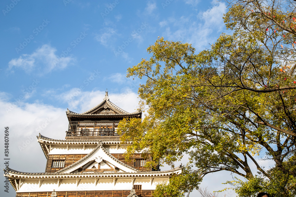 Facade of Hiroshima castle in autumn season against blue sky, called as Crab Castle, an ancient castle in Hiroshima, Japan. It was destroyed by atomic bombing and reconstructed later Facade of Hiroshima castle in autumn season against blue sky, called as Crab Castle, an ancient castle in Hiroshima, Japan. It was destroyed by atomic bombing and reconstructed later