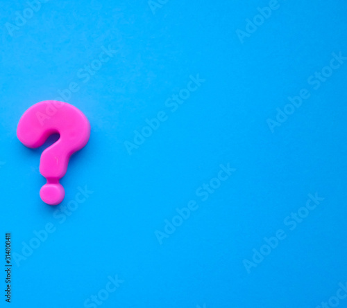 pink question mark on a blue background. Background photo with place for text.