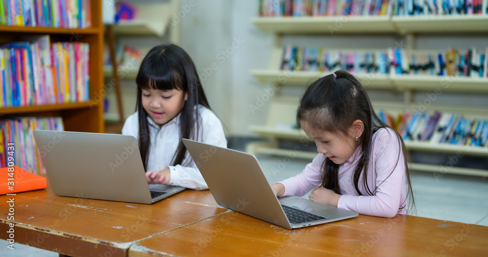 Group of Asian Student Kid Learning to use Laptop in Library with Women Teacher, Shelf of Books in Background, Asian Student Education Concept Group of Asian Student Kid Learning to use Laptop in Library with Women Teacher, Shelf of Books in Background, Asian Student Education Concept