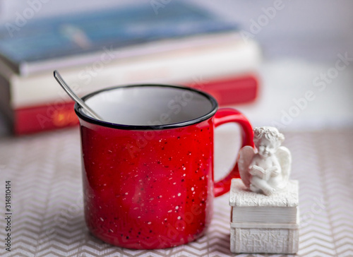 Red mug on a light background and ceramic figurine