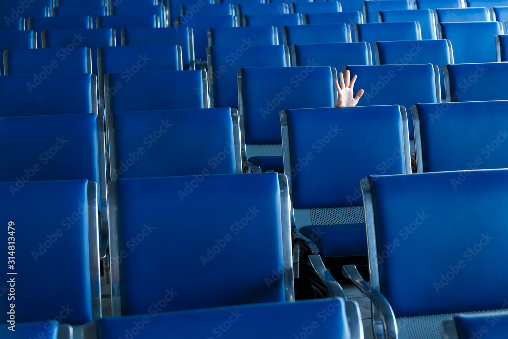 Row of blue seats and a human hand in airport hall