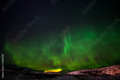 hills, clear starry sky and colorful Northern lights, an incredible natural phenomenon