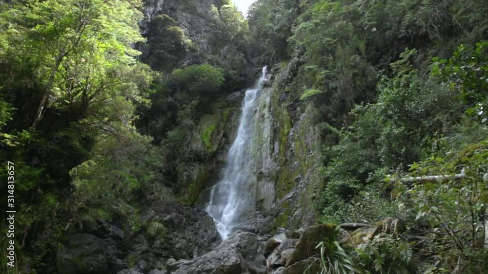 Waterfall in forest. Scenic view of fast flowing large waterfalls in New Zealand landscape. Adventure travel tourism destination. Waterfall in forest. Scenic view of fast flowing large waterfalls in New Zealand landscape. Adventure travel tourism destination.