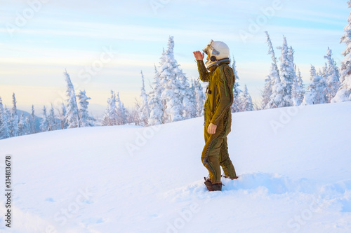 Pilot astronaut is on a snow-capped top. Astronaut in a protective suit and helmet.