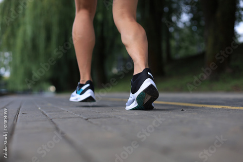 Runner feet running on road closeup on shoe, outdoor at sunset or sunrise.