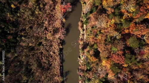 Drone, top down, birds eye view, aerial pedestal up movement over the top of the Rivanna River and surrounding forest displaying bright, vibrant, fall, autumn colors in Virginia, USA., photo