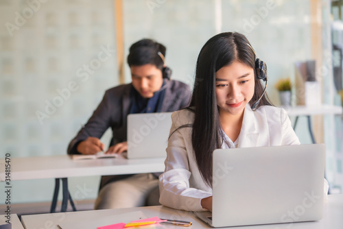 Young female customer support phone operator with headset working in call center.