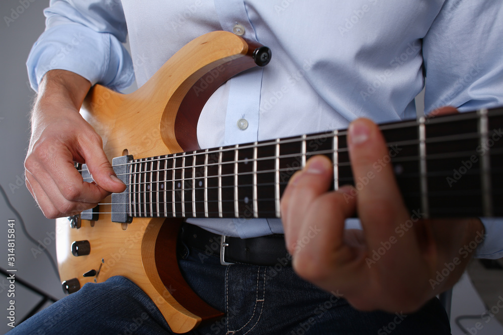 Male arms holding and playing classic shape wooden electric guitar closeup. Six stringed learning musical school education art leisure electrical vintage stage shop having fun enjoying hobby concept Male arms holding and playing classic shape wooden electric guitar closeup. Six stringed learning musical school education art leisure electrical vintage stage shop having fun enjoying hobby concept