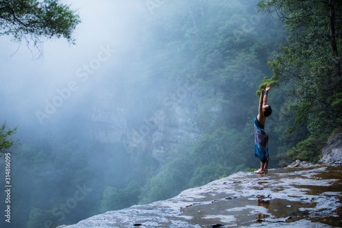 Fotografiet Young beautiful female doing yoga pose above Blue Mountains, Sydney Australia