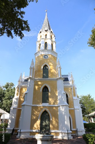 back view of yellow public church and clock with blue sky in the background © Punyaphat