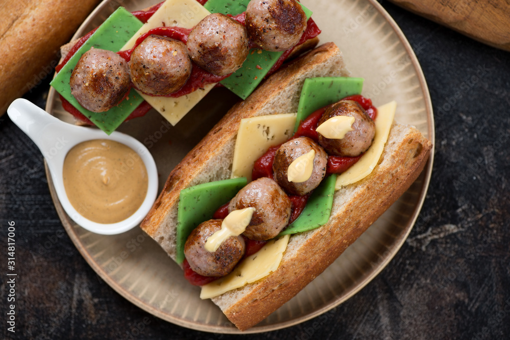 Close-up of sub sandwiches with meatballs and cheese on a beige plate, flatlay, horizontal shot