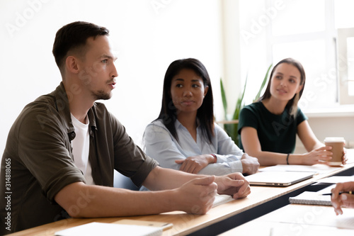 Multiethnic workers listening team leader confident guy at group meeting
