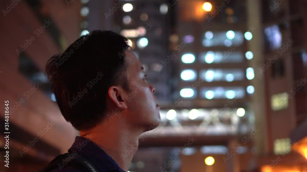 Asian man local Hong Kong looking at apartment residence area at night Asian man local Hong Kong looking at apartment residence area at night