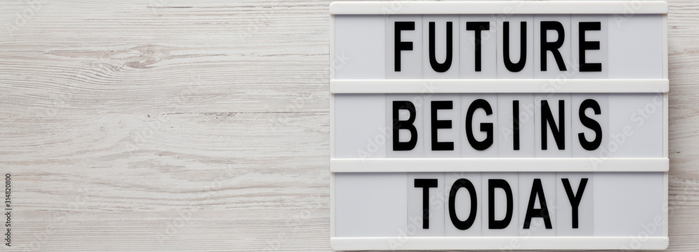 Obraz premium 'Future begins today' words on a modern board on a white wooden background, top view. Overhead, from above, flat lay. Space for text.