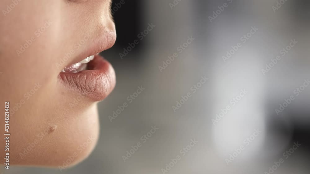 It is a closeup of girl's lips. The lips are shiny. A girl is in a salon. It is a closeup of girl's lips. The lips are shiny. A girl is in a salon.