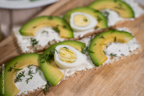 Crisp rye toast with avocado, cream cheese and quail egg on plate