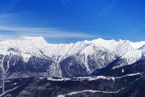 Beautiful environmental view of Caucasus mountain range. Rosa Khotor ski resort. Blue sky and high mountains covered snow.