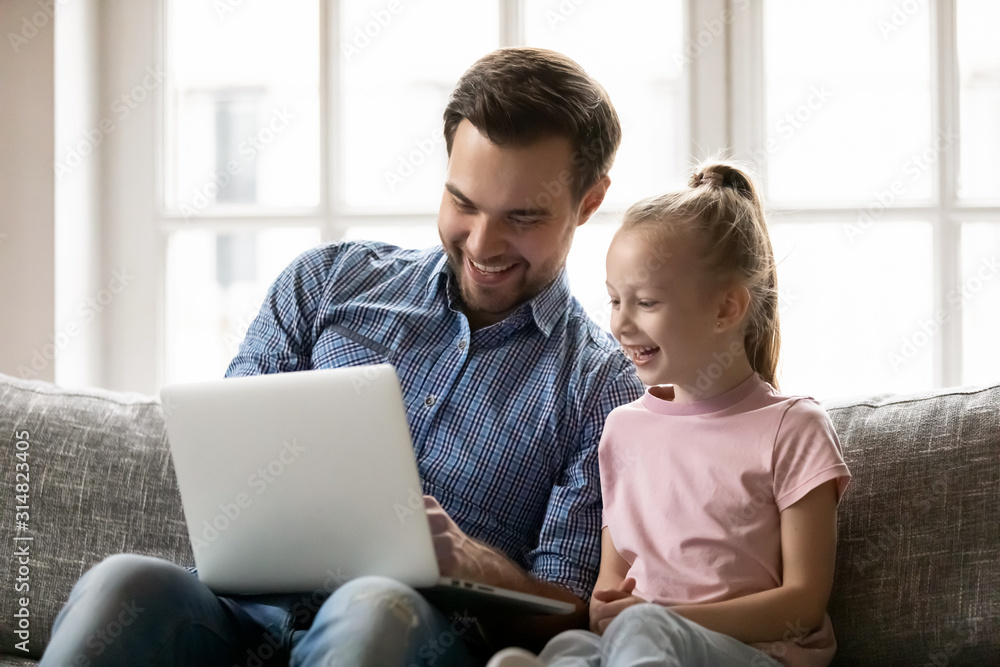 Young dad and little daughter have fun using laptop Young dad and little daughter have fun using laptop
