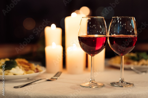 Two Glasses Of Red Wine Standing On Table With Candles