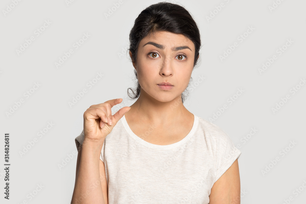 Frustrated millennial indian ethnicity woman demonstrating tiny measurement. Frustrated millennial indian ethnicity woman demonstrating tiny measurement.