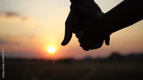 Two lovers joining Hands in 4K Slow motion. Silhouette of Man and Woman holding hands over the Sunset Background. Couple Trust, Love and Valentine's Day concept. photo