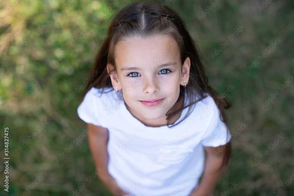 Pretty little girl with long brown hair posing summer nature outdoor. Kid's portrait. Beautiful child's face Pretty little girl with long brown hair posing summer nature outdoor. Kid's portrait. Beautiful child's face